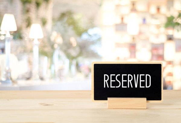 Reserved sign on a table in blur restaurant with bokeh light background